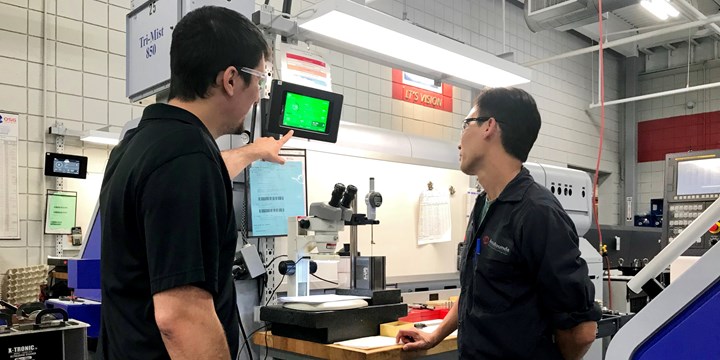 Operators Inspecting a Tablet on Equipment.